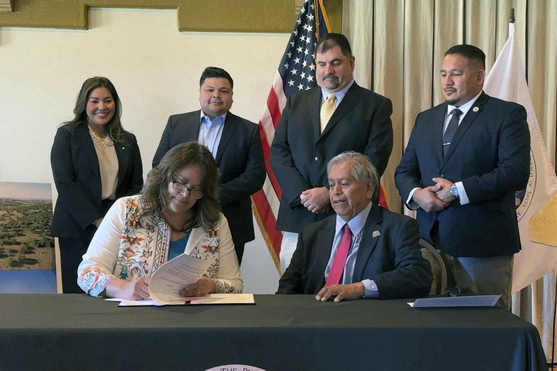 Santa Ana Pueblo Gov. Myron Armijo, seated right, watches as Bureau of Indian Affairs Southwest Regional Director Patricia Mattingly signs documents placing into trust ancestral lands for the benefit of the tribe during a ceremony at Santa Ana Pueblo, N.M. on Wednesday, June 12, 2024. Santa Ana Pueblo has cultural ties to the land and plans to preserve it and restore wildlife habitat. (AP Photo/Susan Montoya Bryan)