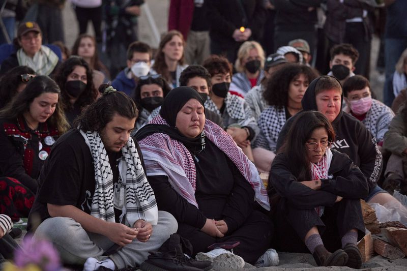 Attendees bow during a silent prayer at a vigil on Alki Beach for Aysenur Ezgi Eygi, a 26-year-old activist from Seattle, who was killed recently in the West Bank, Wednesday, Sept. 11, 2024, in Seattle. (AP Photo/John Froschauer)