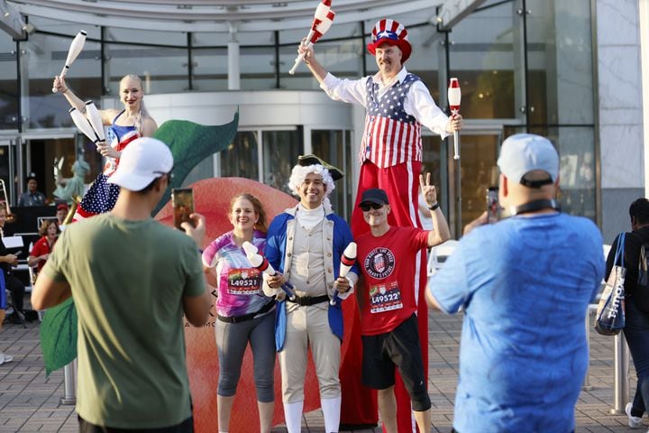 Runners pose with patriotic participants at the start of the 55th running of the Atlanta Journal-Constitution Peachtree Road Race in Atlanta on Thursday, July 4, 2024.   (Miguel Martinez /  AJC)