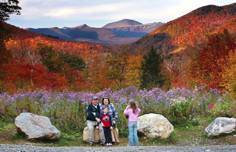 FILE - Wildflowers, fall foliage and the 6,288-foot Mt. Washington serve as a backdrop for Jim and Kathleen Gannon and their son James as their daughter Katarina snaps a picture at Crawford Notch State Park in New Hampshire, Oct. 6, 2006. (AP Photo/Robert F. Bukaty, File)