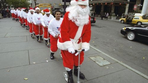 UNITED STATES - CIRCA 2000: Chief Santa Claus Cliff Schneider leads a troop of potential Volunteers of America sidewalk Santas as they scoot through a training session at the Plaza hotel. They were told not to eat garlic or raw onions on duty and to keep "Ho-ho-hos" jovial and joyous, among other things learned in "Santa-class." (Photo by Budd Williams/NY Daily News Archive via Getty Images)