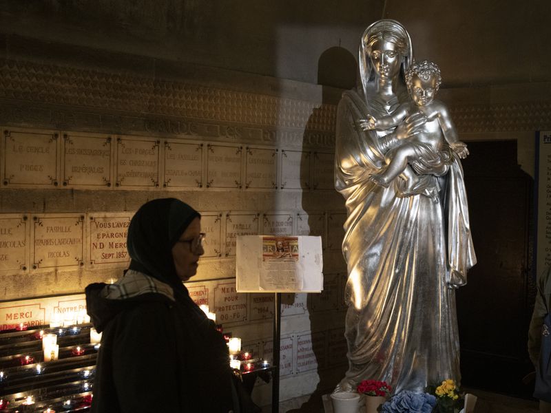 A Muslim woman walks by an icon of the Virgin Mary and Jesus at the Notre Dame de la Garde Basilica in Marseille, southern France, Friday, April 19, 2024. (AP Photo/Daniel Cole)