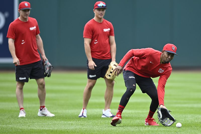 Washington Nationals' Jacob Young, left, with Nationals' Alex Call watch newly arrived teammate from the minor leagues, Darren Baker, right, field a ground ball during outfield practice before a baseball game against the Chicago Cubs, Sunday, Sept. 1, 2024, in Washington. (AP Photo/John McDonnell)