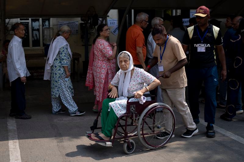 An elderly voter in a wheelchair shows her index finger marked with an indelible ink after she cast her vote in the sixth round of polling in India's national election in New Delhi, India, Saturday, May 25, 2024. (AP Photo/Altaf Qadri)