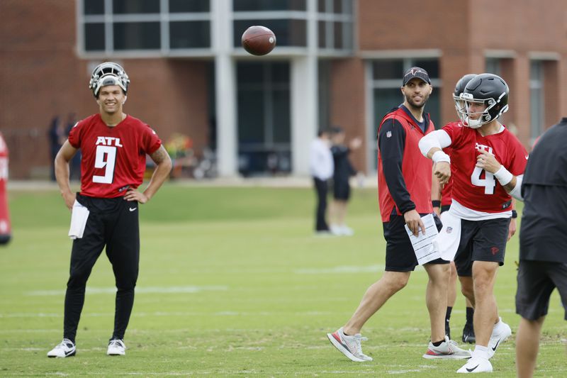 Falcons quarterback Taylor Heinicke (4) throws the ball as Falcons offensive coordinator and quarterback Desmond Ridder (9) looks during a minicamp at the Atlanta Falcons Training Camp on Wednesday, June 14, 2023, in Flowery Branch, Ga.
 Miguel Martinez / miguel.martinezjimenez@ajc.com