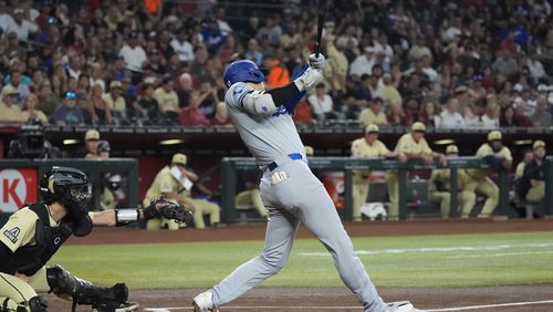 Los Angeles Dodgers designated hitter Shohei Ohtani, right, of Japan, connects for a home run as Arizona Diamondbacks catcher Adrian Del Castillo, left, looks on during the first inning of a baseball game Saturday, Aug. 31, 2024, in Phoenix. (AP Photo/Ross D. Franklin)