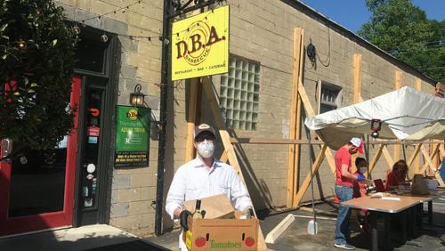 D.B.A. Barbecue owner Matt Coggin carries an order for pickup. “We ll get through it,” Coggin said of keeping the business afloat during the current pandemic. LIGAYA FIGUERAS / LIGAYA.FIGUERAS@AJC.COM