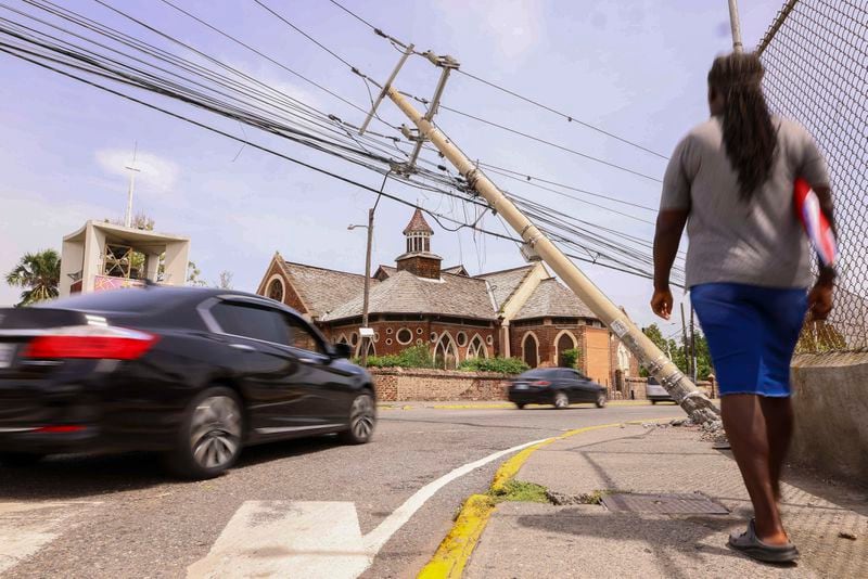 Cars drive under a leaning utility pole in the aftermath of Hurricane Beryl in Kingston, Jamaica, Thursday, July 4, 2024. (AP Photo/Leo Hudson)