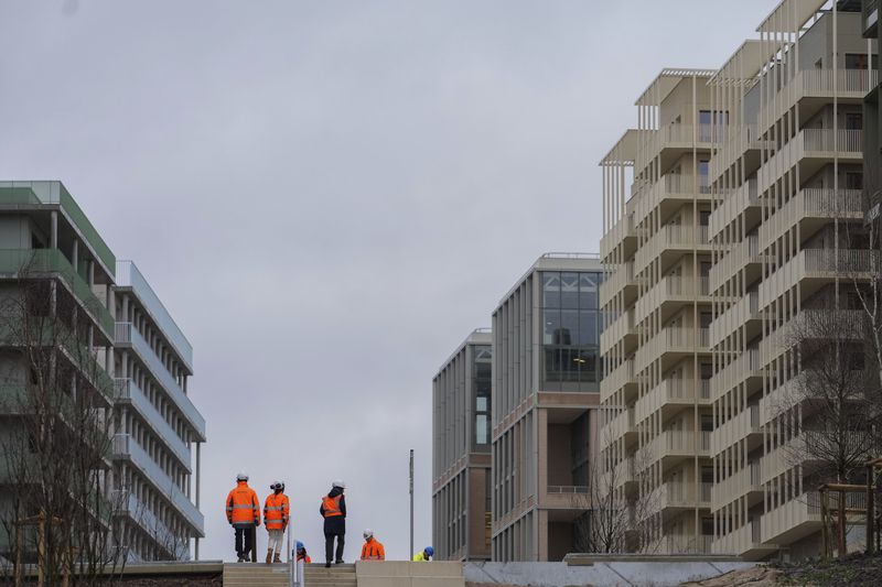 FILE - Workers stand among the buildings of the Olympic village, in Saint-Denis, north of Paris Wednesday, Feb. 28, 2024. The U.S. Olympic team is one of a handful that will supply air conditioners for their athletes at the Paris Games in a move that undercuts organizers' plans to cut carbon emissions. (AP Photo/Thibault Camus, File)