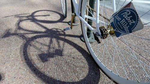 A fix bike with a Pabst Blue Ribbon coaster tucked into the spokes sits locked to a bike rack. Ben Gray / bgray@ajc.com