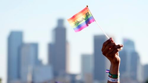 FILE - A pride flag is waved against the downtown Los Angeles skyline during the LA Pride in the Park festival at Los Angeles State Historic Park, June 8, 2024, in Los Angeles. (AP Photo/Chris Pizzello, File)