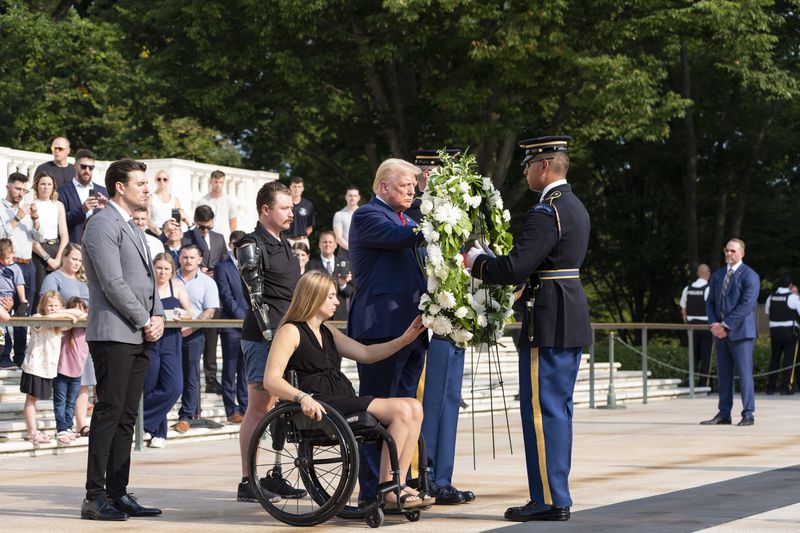 Marlon Bateman, left, former Marine Sgt. Tyler Vargas, second from left, former Marine Cpl. Kelsee Lainhart, center, and Republican presidential nominee former President Donald Trump place a wreath at the Tomb of the Unknown Solider in honor of the 13 service members killed at Abbey Gate, at Arlington National Cemetery, Monday, Aug. 26, 2024, in Arlington, Va. (AP Photo/Alex Brandon)