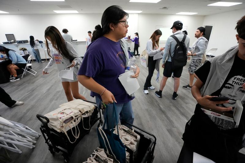 Poder In Action canvassers gather their kits prior to a neighborhood canvassing voter outreach event Tuesday, Sept. 3, 2024, in Phoenix. (AP Photo/Ross D. Franklin)