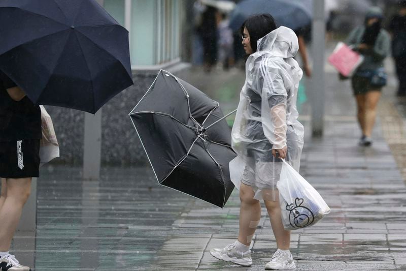 People holding umbrella, struggles with the strong wind as a typhoon is approaching in Fukuoka, western Japan, Thursday, Aug. 29, 2024. (Kyodo News via AP)