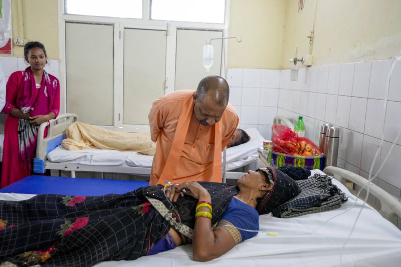 Uttar Pradesh State Chief Minister Yogi Adityanath, talks to a woman who was injured in a stampede as she receives treatment at Hathras district hospital, Uttar Pradesh, India, Wednesday, July 3, 2024. Thousands of people at a religious gathering rushed to leave a makeshift tent, setting off a stampede Tuesday that killed more than hundred people and injured scores. (AP Photo/Rajesh Kumar Singh)
