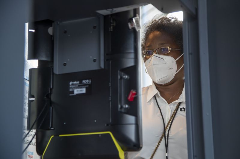 A system specialist for the Fulton County department of registration and elections [name withheld] inspects each voting machine on the floor at State Farm Arena in Atlanta, Wednesday, October 7, 2020. (Alyssa Pointer / Alyssa.Pointer@ajc.com)