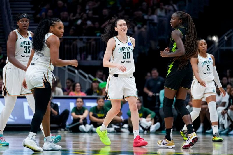 New York Liberty forward Breanna Stewart (30) smiles during the second half of a WNBA basketball game as forward Jonquel Jones (35) and forward Betnijah Laney-Hamilton, second from left, look on against Seattle Storm center Ezi Magbegor, Friday, Aug. 30, 2024, in Seattle. The Liberty won 98-85. (AP Photo/Lindsey Wasson)