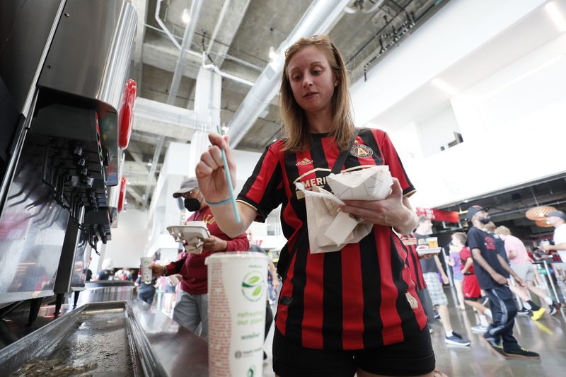 Kate Walton from Atlanta puts the new biodegradable straw into her soft drink at the Mercedes-Benz Stadium on Sunday, July 17, 2022. The new blue drinking straw breaks down in the environment faster than a typical straw. Miguel Martinez /miguelmartinezjimenezajc.com