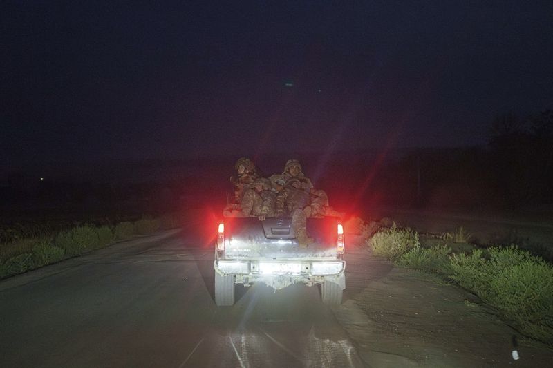 Ukrainian servicemen ride in a trunk of pickup truck towards their positions at the frontline in Donetsk region, Ukraine, on Wednesday, Aug. 21, 2024. (AP Photo/Evgeniy Maloletka)