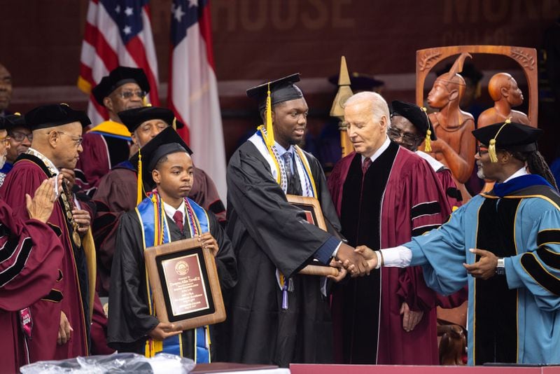 Morehouse valedictorian DeAngelo Jeremiah Fletcher (center) is seen as President Joe Biden (right) and Morehouse President David A. Thomas (far left), look on at the commencement ceremony at Morehouse College in Atlanta on Sunday, May 19, 2024. (Arvin Temkar / AJC)