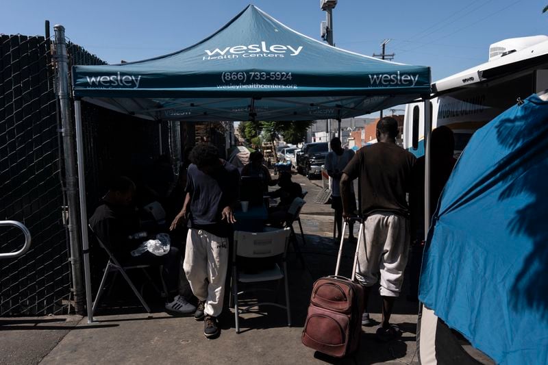 Homeless people sign up for medical services outside Wesley Health Centers' mobile clinic in the Skid Row area of Los Angeles, Tuesday, Aug. 27, 2024. (AP Photo/Jae C. Hong)