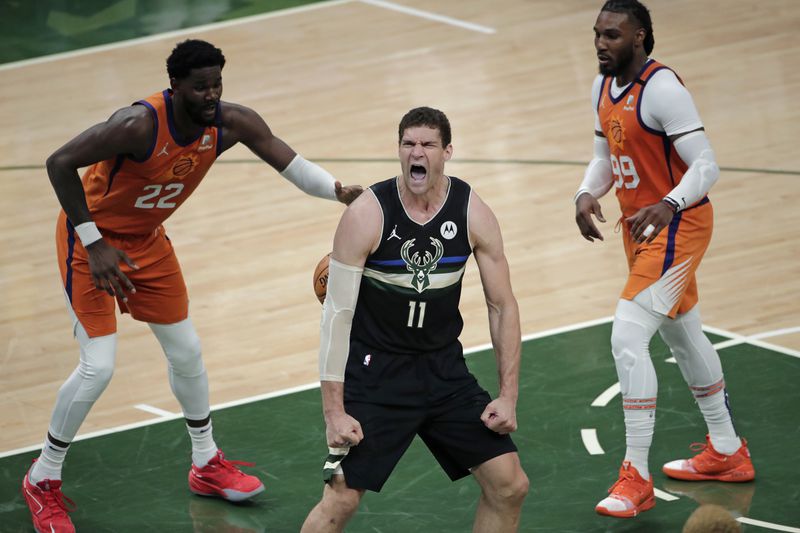 Milwaukee Bucks center Brook Lopez (11) reacts after a slam dunk in front of Phoenix Suns center Deandre Ayton (22) and forward Jae Crowder (99) during the second half of Game 6 of basketball's NBA Finals Tuesday, July 20, 2021, in Milwaukee. (AP Photo/Aaron Gash)