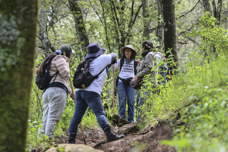 Catholic nun Paola Clerico, center, Anglican priest Rev. Arturo Carrasco, right, accompany members of the search collective "Uniendo Esperanzas" or Uniting Hope, as they take a break from their search for human remains in a forest in the State of Mexico, Mexico, Friday, Aug. 16, 2024. Second from left is Angelica Montelongo whose husband Rafael went missing when he did not return home from work in 2021. At far left is a theologist who works with Clerico and is studying anthropology. (AP Photo/Ginnette Riquelme)