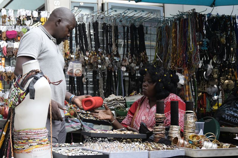 People in a street vendor stall in the Harlem neighborhood of New York, Thursday, Aug. 15, 2024. (AP Photo/Pamela Smith)