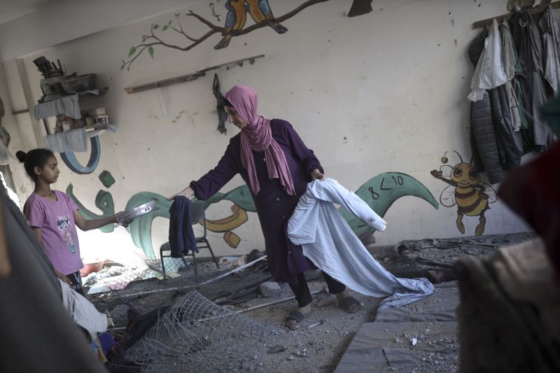 A Palestinian family retrieves their belongings from a heavily damaged UNRWA school sheltering displaced persons the day after a nearby house was targeted by Israeli bombardment in Khan Younis, southern Gaza Strip, Friday, June 21, 2024. (AP Photo /Jehad Alshrafi)