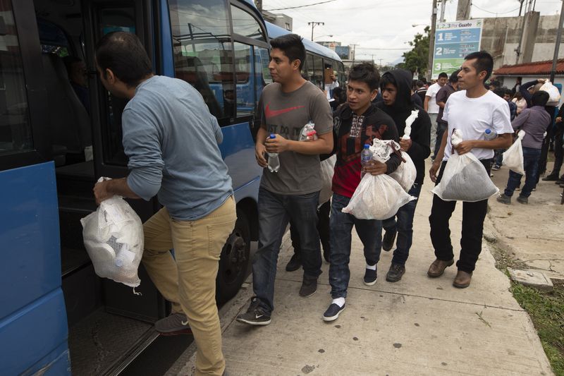 FILE - Guatemalan men who were deported from the United States, board a bus after arriving at the Air Force Base in Guatemala City, on July 16, 2019. (AP Photo/Moises Castillo, File)