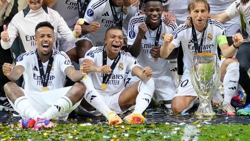 Real Madrid's Eder Militao, Kylian Mbappe, Vinicius Junior, and Luka Modric pose with the trophy after winning the UEFA Super Cup Final soccer match between Real Madrid and Atalanta at the Narodowy stadium in Warsaw, Poland, Wednesday, Aug. 14, 2024. Real Madrid won 2-0. (AP Photo/Darko Bandic)