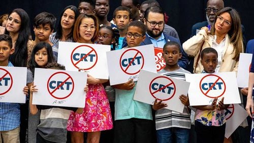 Schoolchildren holding signs against the concept of critical race theory stand on stage as Florida Gov. Ron DeSantis addresses the crowd before signing House Bill 7, titled the "Individual Freedom" bill but also dubbed the “Stop WOKE Act,” during a news conference at Mater Academy Charter Middle/High School in Hialeah Gardens, Fla., on April 22, 2022. (Daniel A. Varela/Miami Herald/TNS)