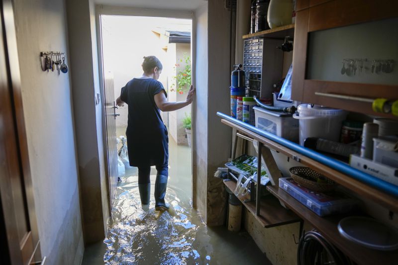 Zuzana Kublova wades through her flooded family home, in Bohumin, Czech Republic, Tuesday, Sept. 17, 2024. (AP Photo/Darko Bandic)