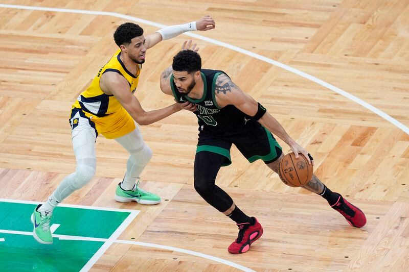 Boston Celtics forward Jayson Tatum (0) is defended by Indiana Pacers guard Tyrese Haliburton, left, during the first half of Game 2 of the NBA Eastern Conference basketball finals Thursday, May 23, 2024, in Boston. (AP Photo/Michael Dwyer)