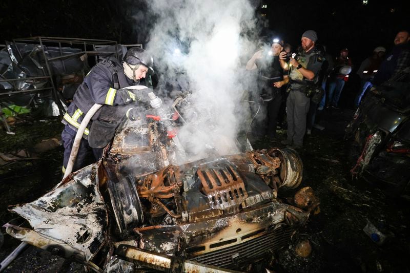 A firefighter extinguishes a burning vehicle after a Russian strike on a residential building in Kharkiv, Ukraine early Sunday Sept. 22, 2024. (Kharkiv Regional Military Administration via AP)