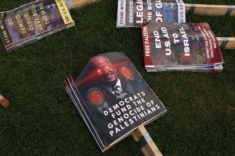 Protest signs featuring prominent Democrats sit on the ground Monday, Aug. 19, 2024, at Union Park in Chicago, with protesters' demands included ending aid to Israel and helping the Palestinian people. (AP Photo/Martha Irvine)