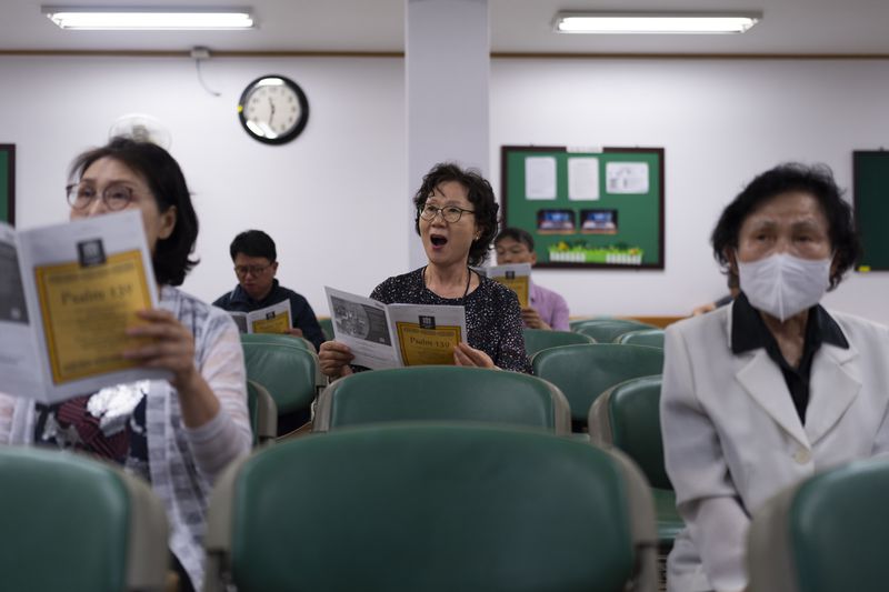 Choi Young-kyung, center, a retired piano tutor, sings in the choir practice room at Youngnak Presbyterian Church in Seoul, Sunday, May 26, 2024. "I don't think North Korea can easily start a war as long as the U.S. military is stationed in South Korea. They know that the U.S. will retaliate if they attack us," said Choi. (AP Photo/Jae C. Hong)