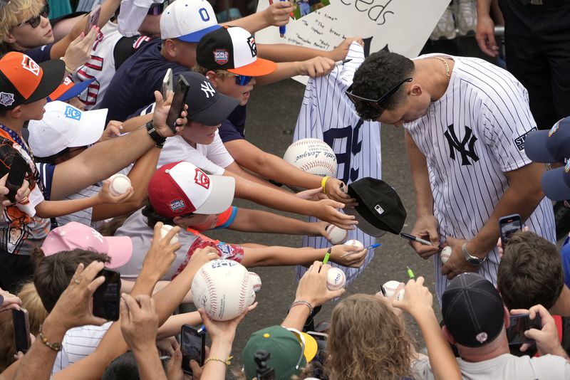 New York Yankees' Aaron Judge signs autographs for fans as the New York Yankees arrive at the Little League World Series Complex to watch the Little League World Series tournament in South Williamsport, Pa., Sunday, Aug. 18, 2024. (AP Photo/Tom E. Puskar)