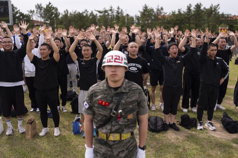 Standing behind a drill instructor, recruits wave to their family members during an induction ceremony at a Marine Corps base in Pohang, South Korea, Monday, May 27, 2024. In South Korea, military service is mandatory for most men. (AP Photo/Jae C. Hong)