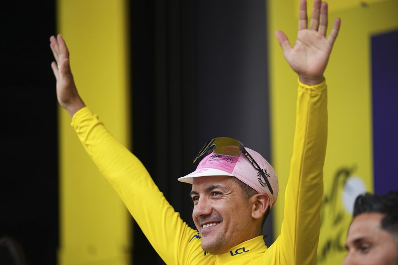 Ecuador's Richard Carapaz, wearing the overall leader's yellow jersey, celebrates on the podium after the third stage of the Tour de France cycling race over 230.8 kilometers (143.4 miles) with start in Piacenza and finish in Turin, Italy, Monday, July 1, 2024. (AP Photo/Daniel Cole)