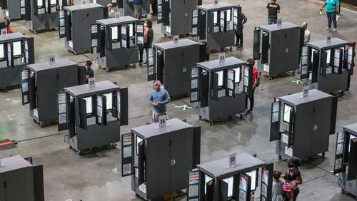 Voters finally got to the machines after a glitch forestalled voting on Monday, Oct. 12, 2020 at State Farm Arena in downtown Atlanta. Eager Georgia voters swarmed to polling places Monday morning, waiting in lines created by high turnout and technical problems at the start of three weeks of early voting before Election Day. A glitch with voter check-in computers held up voters at Georgia’s largest early voting site at State Farm Arena. Lines stopped after voters received an “invalid card” error when inserting green voter access cards into touchscreens. Poll workers had to reboot the arena’s 60 voter check-in tablets and re-import voter information, said Fulton Elections Director Richard Barron. “We apologize to all the voters,” Barron said. (John Spink / John.Spink@ajc.com)