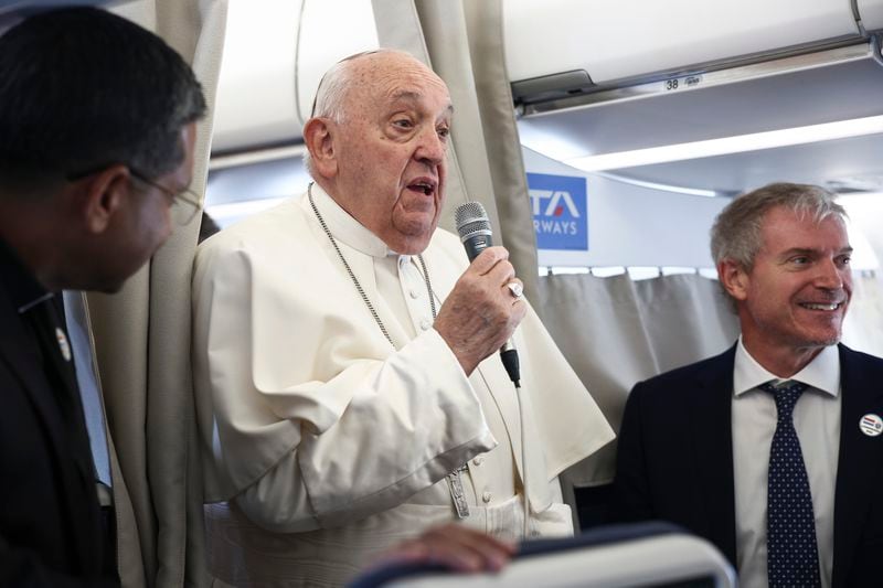 Pope Francis, center, speaks to the media aboard his flight bound for Luxembourg, where he will start a four-day apostolic journey in Luxembourg and Belgium, Thursday, Sept. 26, 2024. (Guglielmo Mangiapane/Pool Photo via AP)