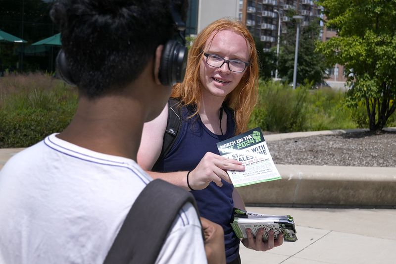 Activist Liz Rathburn hands out a flyer on the University of Illinois-Chicago campus Wednesday, Aug. 14, 2024, about two marches in support of Palestine, during the Democratic National Convention next week in Chicago. (AP Photo/Charles Rex Arbogast)