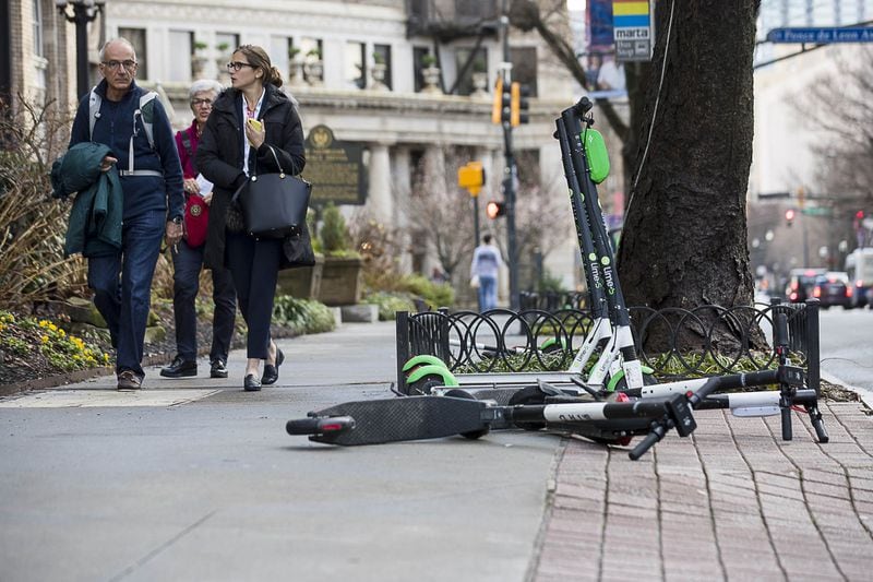  Pedestrians walk past Lime and Bird scooters that are parked on the sidewalk of Peachtree Street in Midtown on Jan. 4, 2019. (ALYSSA POINTER/ALYSSA.POINTER@AJC.COM)