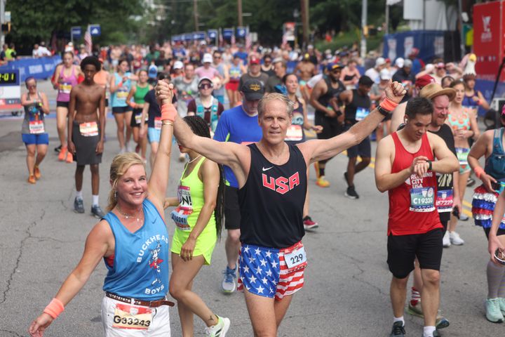 Evan Owns and Chip Owens celebrate at the finish of the 55th running of the Atlanta Journal-Constitution Peachtree Road Race in Atlanta on Thursday, July 4, 2024.   (Jason Getz / AJC)