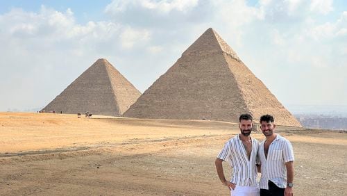 This 2023 photo shows Stefan Arestis, right, and Sebastien Chaneac, at the Pyramids in Egypt. The two are globetrotters who run the LGBTQ+-focused travel blog The Nomadic Boys. They published a travel guide this year, “Out in the World: The Gay Guide to Travelling with Pride.” (The Nomadic Boys via AP)