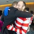 Jima Parkis, dressed in an American flag, hugs his friend James Watson, who emigrated from England, after the Naturalization Ceremony for 150 new citizens in the Gwinnett Justice and Administration Center auditorium Tuesday July 2 2024. (Steve Schaefer / AJC)