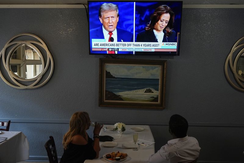 People watch the presidential debate between Republican presidential nominee former President Donald Trump and Democratic presidential nominee Vice President Kamala Harris, Tuesday, Sept. 10, 2024, in Oakland, Calif. (AP Photo/Godofredo A. Vásquez)