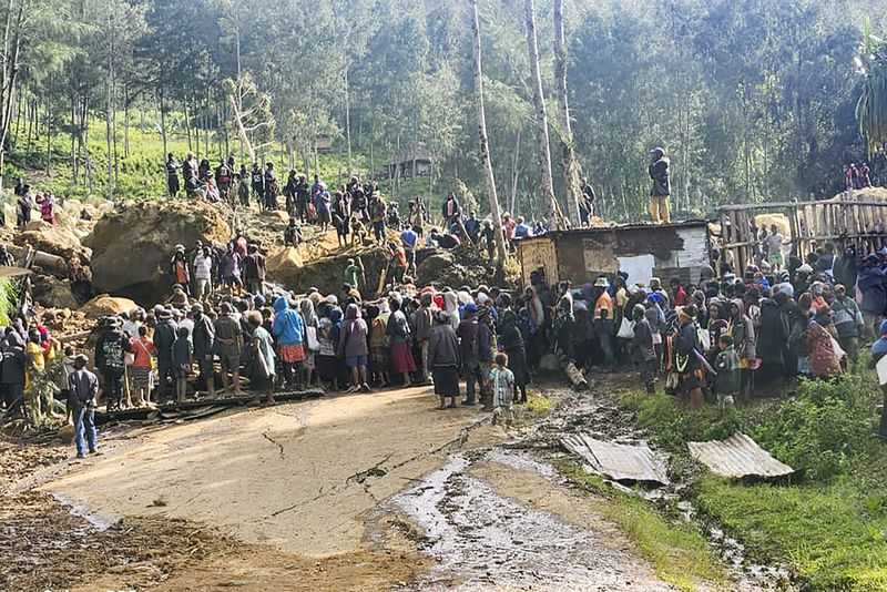 In this image supplied by the International Organization for Migration, villagers react after a body was discovered amongst the debris form a landslide in the village of Yambali in the Highlands of Papua New Guinea, Monday, May 27, 2024. (Mohamud Omer/International Organization for Migration via AP)