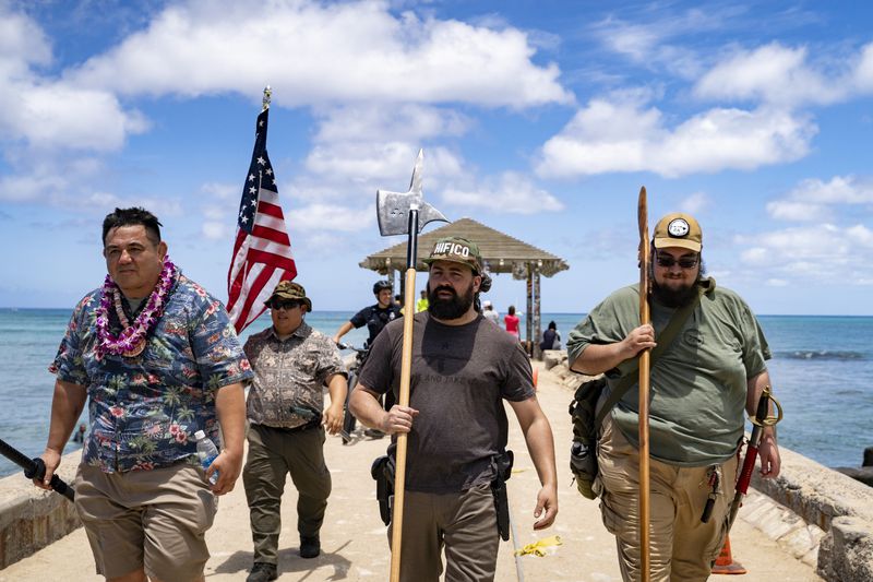 Members of Hawaii Firearms Coalition walk around Waikiki with their non-firearm weapons on Saturday, June 22, 2024, in Honolulu, Hawaii. (AP Photo/Mengshin Lin)